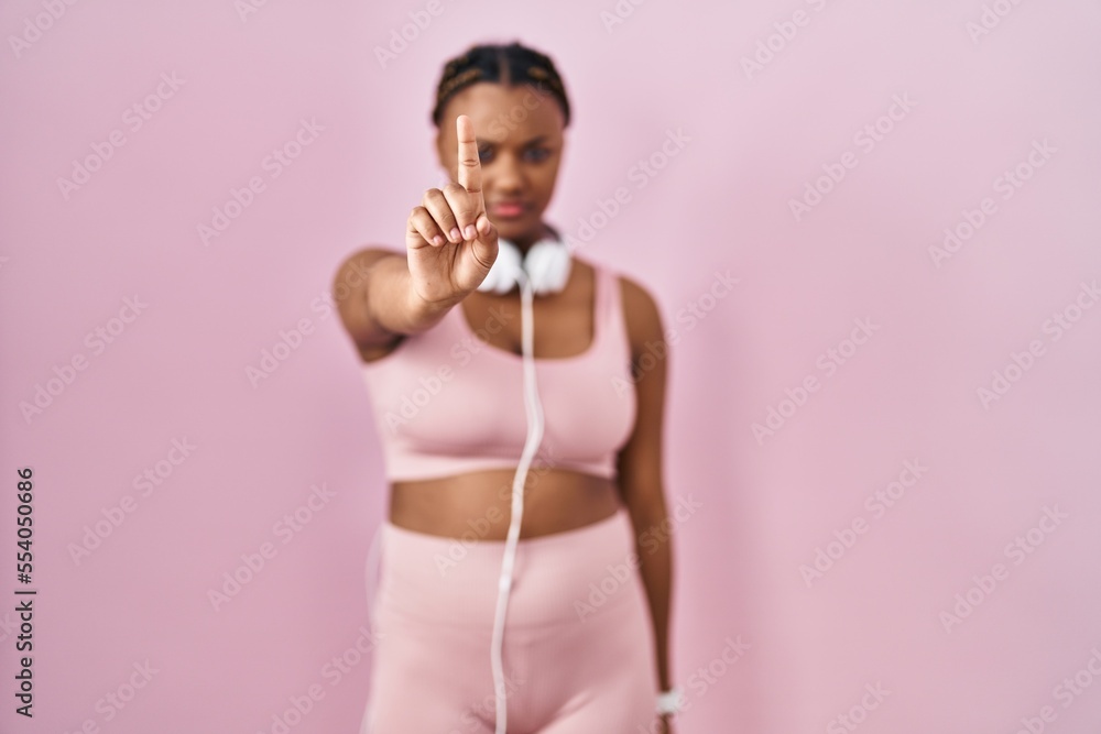 African american woman with braids wearing sportswear and headphones pointing with finger up and angry expression, showing no gesture African american woman with braids wearing sportswear and headphones pointing with finger up and angry expression, showing no gesture