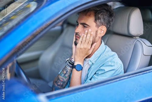 Young hispanic man stressed driving car at street © Krakenimages.com