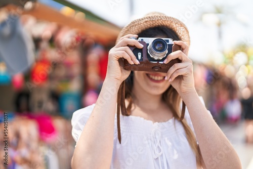 Young hispanic woman tourist smiling confident using camera at street market