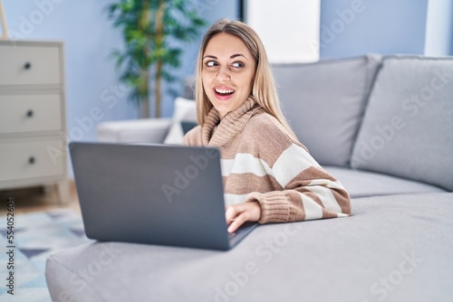 Young woman using laptop sitting on floor at home