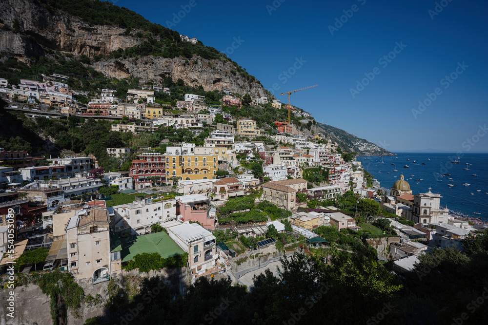 Positano with hotels and houses on hills leading down to coast, comfortable beaches and azure sea on Amalfi Coast in Campania, Italy.