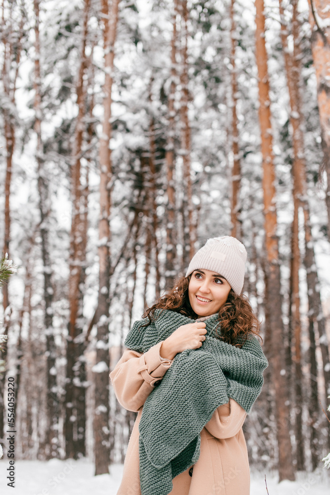 A smiling girl with a green scarf in a coat stands in the snow in winter and looks away A smiling girl with a green scarf in a coat stands in the snow in winter and looks away