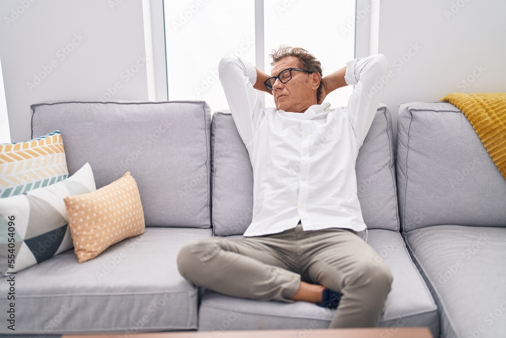 Middle age man relaxed with hands on head sitting on sofa at home Middle age man relaxed with hands on head sitting on sofa at home
