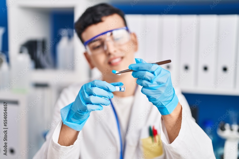 Young non binary man scientist smiling confident holding pills at laboratory Young non binary man scientist smiling confident holding pills at laboratory