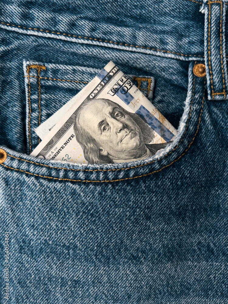 Close up detailed shot of dollars in blue jeans pocket. Money in the pocket of jeans. 100 one hundred bucks Close up detailed shot of dollars in blue jeans pocket. Money in the pocket of jeans. 100 one hundred bucks