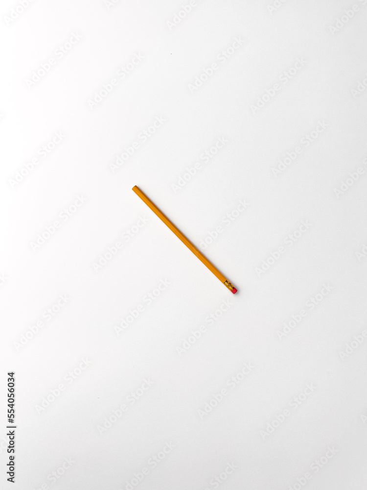 Stationery on office table. Isolated yellow pencil with red rubbered tip on the white background Stationery on office table. Isolated yellow pencil with red rubbered tip on the white background
