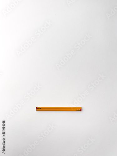 Stationery on office table. Isolated yellow pencils with red rubbered tip on the white background photo