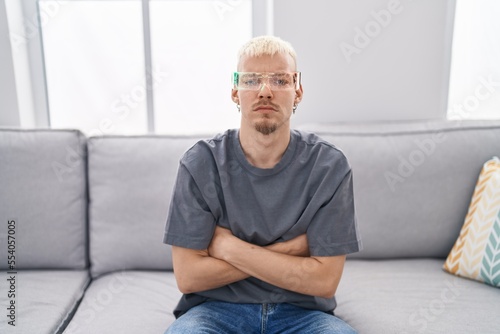 Young caucasian man wearing virtual reality glasses skeptic and nervous, disapproving expression on face with crossed arms. negative person.