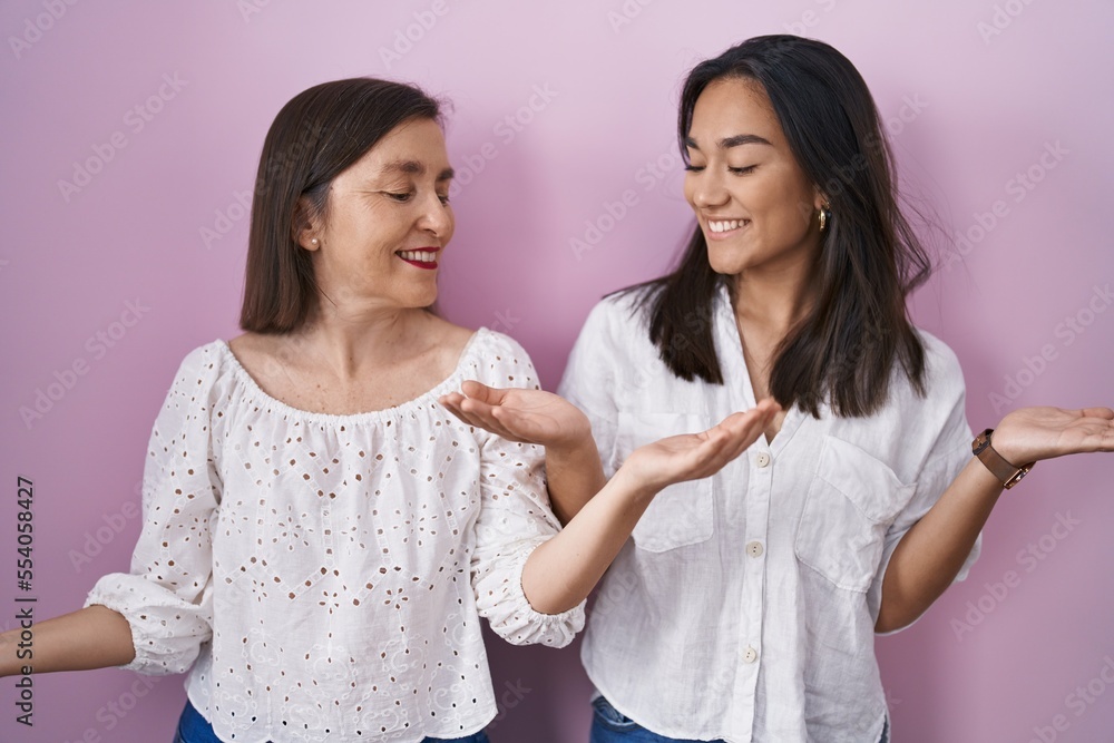 Hispanic mother and daughter together smiling showing both hands open palms, presenting and advertising comparison and balance Hispanic mother and daughter together smiling showing both hands open palms, presenting and advertising comparison and balance