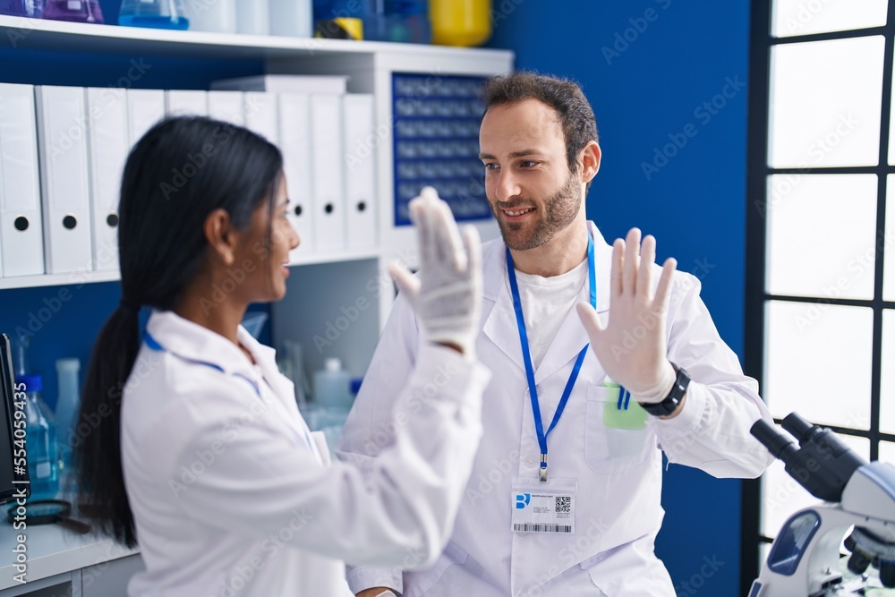 Man and woman scientists smiling confident high five at laboratory