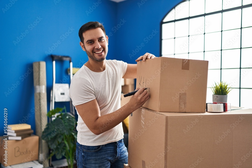 Young hispanic man smiling confident writing on cardboard box at new home Young hispanic man smiling confident writing on cardboard box at new home