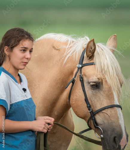 A beautiful young girl in a farmer's field next to the horses.