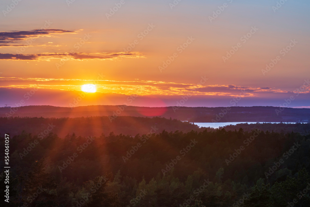 View of the sun setting over the forest and sea. Lemland, Åland Islands. Finland. View of the sun setting over the forest and sea. Lemland, Åland Islands. Finland.