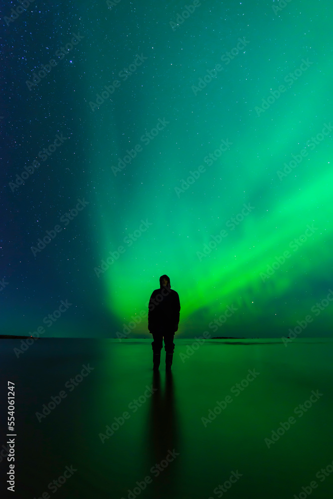 Silhouette of a person. Northern lights and reflections in the sea in the background. Storsand, Jakobstad/Pietarsaari. Finland
