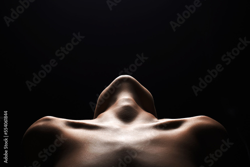 shoulders of a naked woman. Nude silhouette under light in the dark