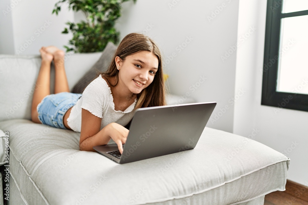 Adorable girl using laptop lying on sofa at home Adorable girl using laptop lying on sofa at home