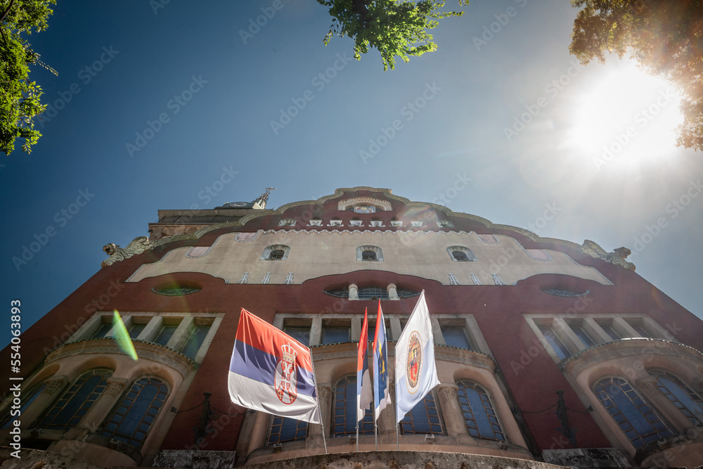 Subotica city flag with the coat of arms of the city on the gradska kuca, the city hall. It is the official visual and symbol of Subotica, one of the main cities of Vojvodina, in Serbia. .. - obrazy, fototapety, plakaty 