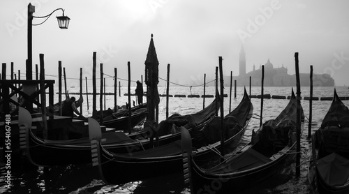 Panorama of Venice Italy in black and white. Foggy morning atmosphere on the Canale Grande with silhouettes of Gondolas and mist above the water and church on Giudecca Island in winter season. © ON-Photography