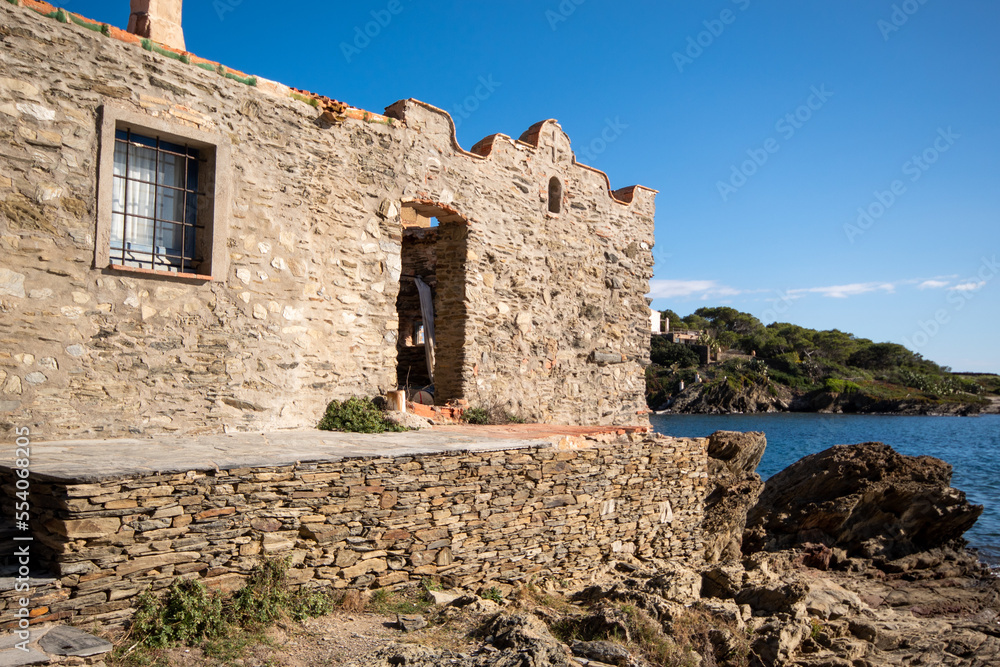 Casa de piedra abandonada en medio de la nada justo enfrente del tranquilo mar en el pueblo pesquero de Cadaqués bajo un precioso cielo azul.