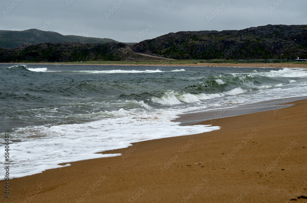 Surf on the coastline of the north sea with a mountainous coast in the background Surf on the coastline of the north sea with a mountainous coast in the background