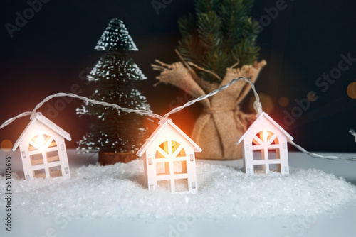 Garland in the form of wooden houses with yellow bulbs close-up on white-black background. Christmas  new year background