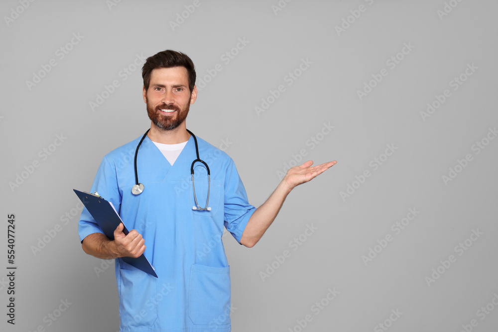 Happy doctor with stethoscope and clipboard on light grey background. Space for text Happy doctor with stethoscope and clipboard on light grey background. Space for text
