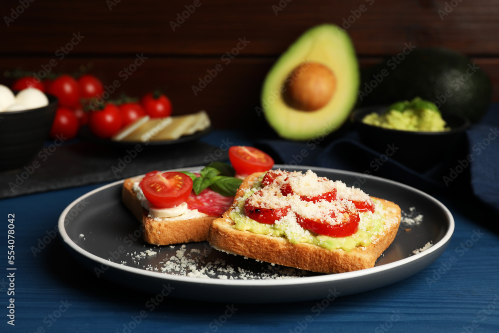 Tasty toasts with different toppings served on blue wooden table