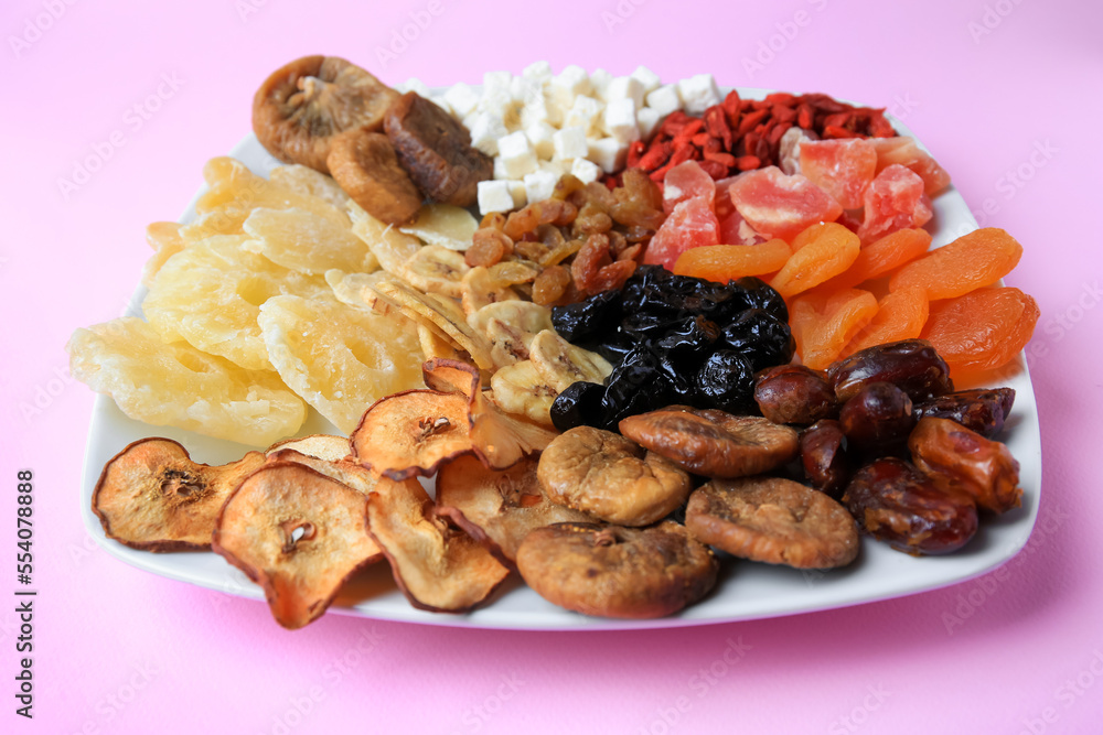 Plate with different dried fruits on violet background, closeup