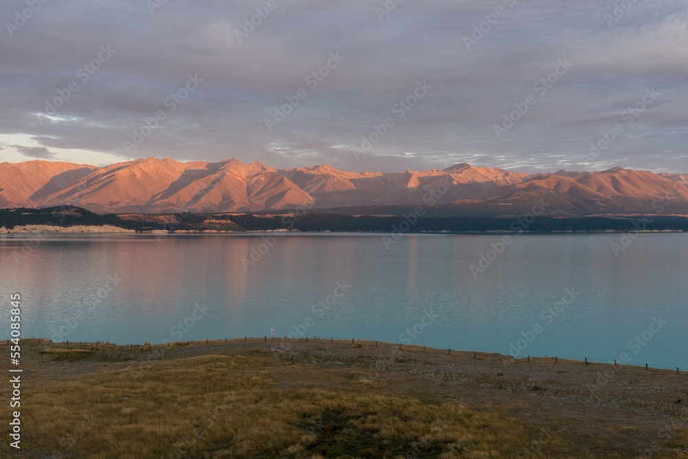 Lake Pukaki mit türkisem Wasser und glühenden Bergen zum Sonnenaufgang.