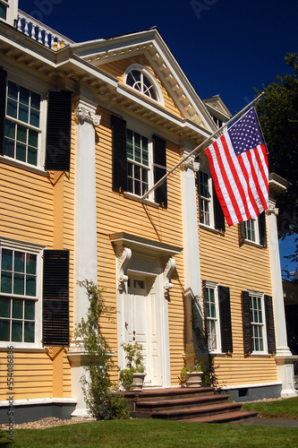 An American flag flies from the yellow historic Home of Poet Henry Wadsworth Longfellow in Cambridge, Massachusetts