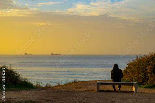 silhouette of a person sitting on a bench at sunset