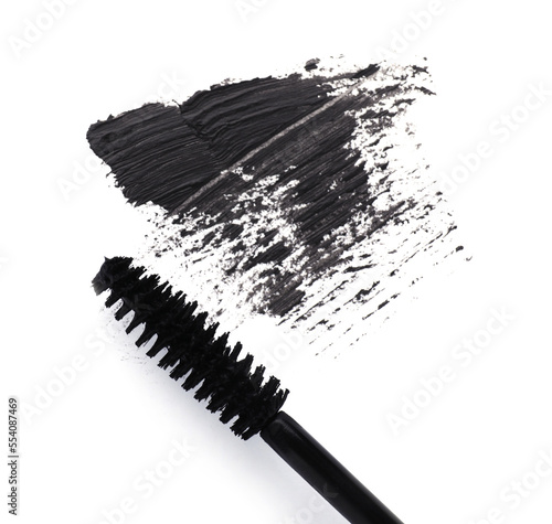 Applicator and black mascara smear on white background, top view