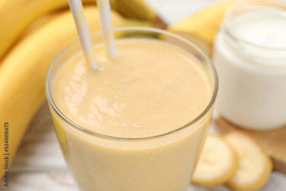 Glass of tasty banana smoothie with straws and ingredients on table, closeup Glass of tasty banana smoothie with straws and ingredients on table, closeup