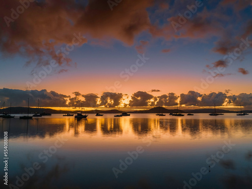 Aerial sunrise waterscape with boats, clouds and reflections
