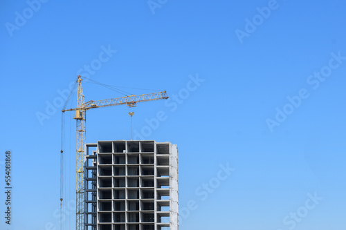A tower crane builds a residential building against the sky. Construction of buildings, construction site.