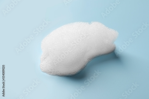 Drop of fluffy soap foam on light blue background