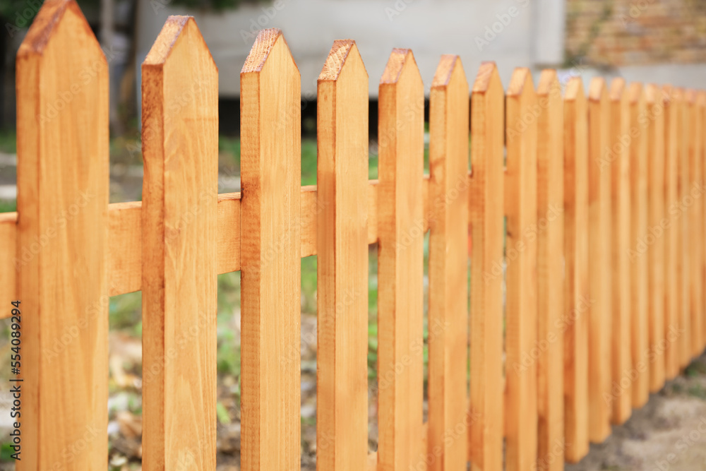 Wooden fence outdoors on sunny day, closeup Wooden fence outdoors on sunny day, closeup