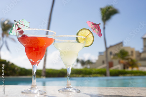 MARGARITAS. CHERRY AND LEMON DAISIES ON THE EDGE OF A POOL ON A SUNNY DAY