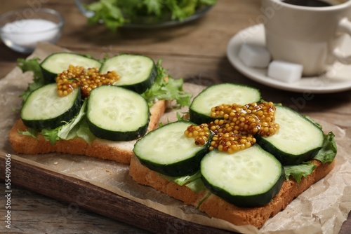 Tasty cucumber sandwiches with arugula and mustard on wooden table, closeup