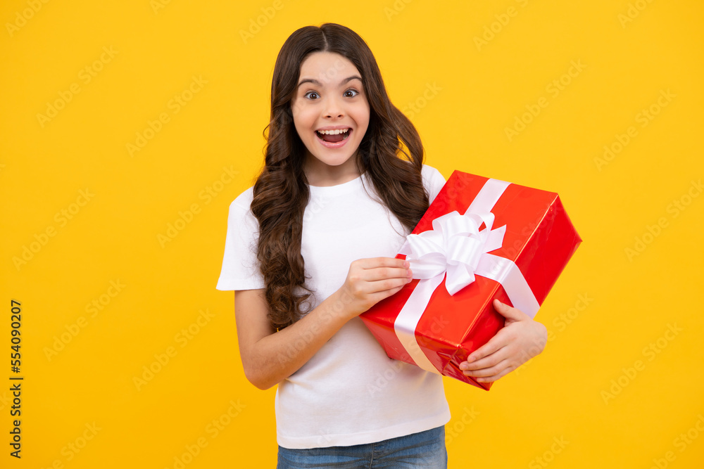 Happy teenager, positive and smiling emotions of child girl. Teenager kid with present box on isolated yellow background. Teen girl giving birthday gift. Present, greeting and gifting concept. Happy teenager, positive and smiling emotions of child girl. Teenager kid with present box on isolated yellow background. Teen girl giving birthday gift. Present, greeting and gifting concept.