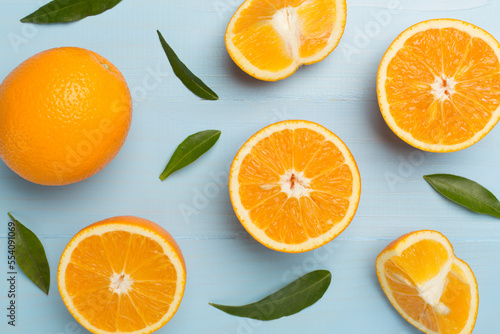 Flat lay with fresh oranges and leaves on wooden background