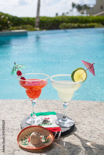 CHERRY AND LEMON DAISIES ON THE EDGE OF A POOL ON A SUNNY DAY WITH A MEXICAN FLAG TABLECLOTH WITH THE PHRASE VIVA MEXICO