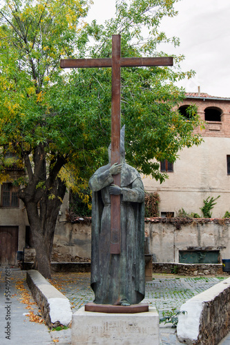 bronze sculpture of an Easter penitent with a cross in a square in Segovia. Spain