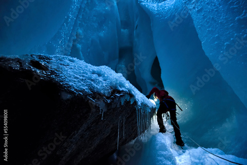 A cave explorer inspects a giant rock inside a moulin, named None Stop, on the Gorner Glacier. photo