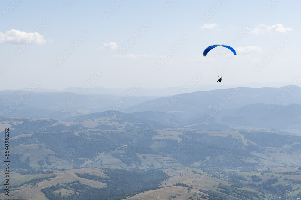 paraglider against the backdrop of a blue sky and a mountain village in Ukraine paraglider against the backdrop of a blue sky and a mountain village in Ukraine