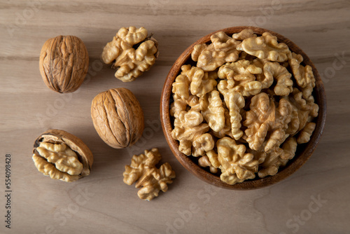 Peeled walnuts and whole walnuts in wooden bowl 