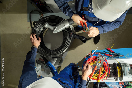 Technician works with cables for plug to charge EV. Electricians use pliers and install cables in plug for working at electric charging station