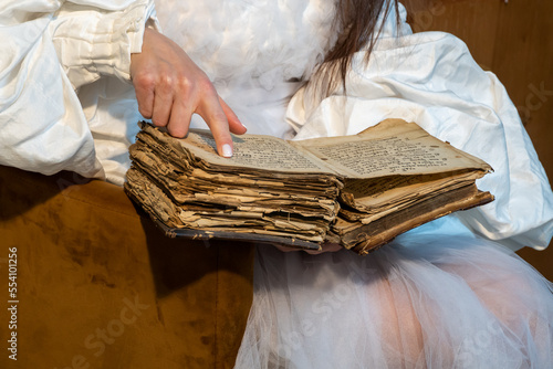 an old book in the hands of a woman. book with old pages. magical history book. old book, manuscript