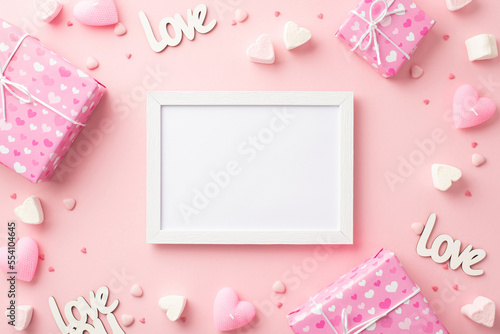 Valentine's Day concept. Top view photo of photo frame present boxes heart shaped marshmallow candles inscriptions love and sprinkles on isolated pastel pink background with copyspace © ActionGP
