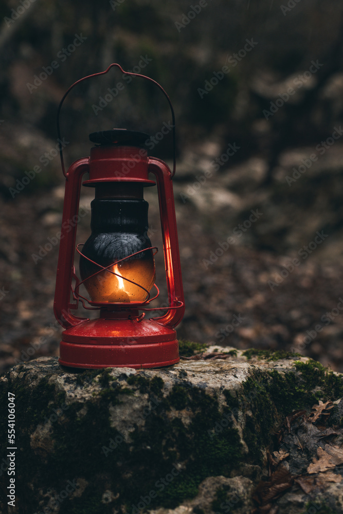 A red kerosene lantern in the autumn forest. Old kerosene lamp.